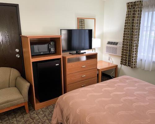 a hotel room with a bed and a tv and a chair at Hudson Inn & Suites in Hudson