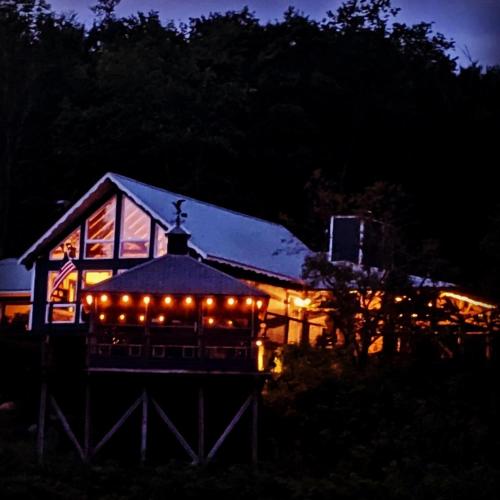 a gazebo with lights in front of a house at night at The Blue House On The Hill Catskills—Views in Claryville