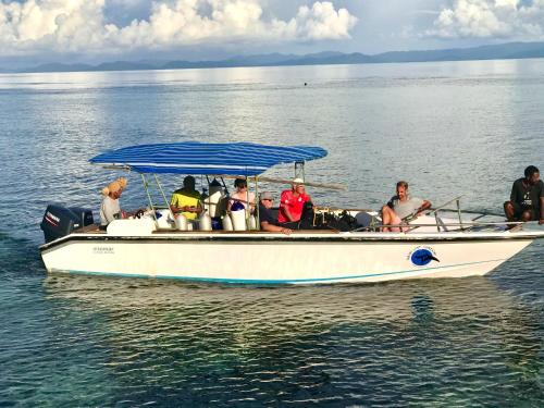TABARI DIVE LODGE في Pulau Mansuar: مجموعة من الناس جالسين على قارب في الماء
