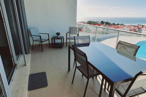 a balcony with a table and chairs and a swimming pool at Brisa do Mar Ap. in Nazaré