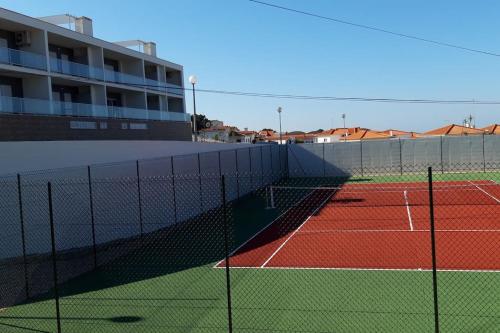 a tennis court with a net in front of a building at Brisa do Mar Ap. in Nazaré