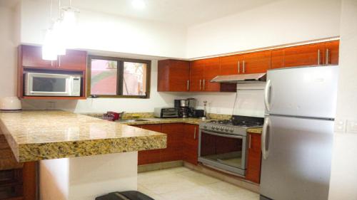 a kitchen with wooden cabinets and a stainless steel refrigerator at Los Tules Ocean Front Condo ,With Amazing Ocean View by Kivoya in Puerto Vallarta