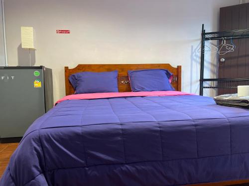 a large bed with a purple blanket and blue pillows at SMILE HOME GUESTHOUSE in Rayong