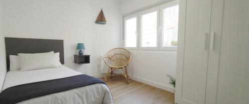 um quarto com uma cama, uma cadeira e uma janela em Dúplex Costa de Fisterra II em Finisterre