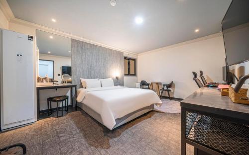 a bedroom with a large white bed and a kitchen at St. 179 Incheon Hotel in Incheon