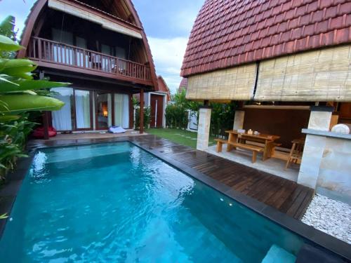 a villa with a swimming pool in front of a house at Bhumi Lovina Residence & Villa in Singaraja