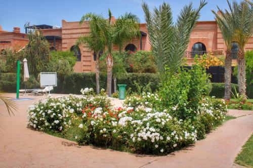 a garden with flowers in front of a building at Duplex Atlas Golf Resort Pοοl νieω Seriniτყ & Cαlm in Marrakesh