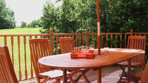 une table et des chaises en bois sur une terrasse avec un parasol dans l'établissement La maison de Laujol, à Moissac