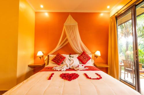 a bedroom with a bed with red flowers on it at Pondok Kutuh Guest House in Ubud