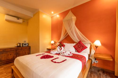 a bedroom with a large white bed with red pillows at Pondok Kutuh Guest House in Ubud