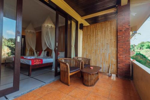 a balcony with a bed and a table and chairs at Pondok Kutuh Guest House in Ubud