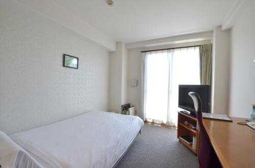 a hotel room with a bed and a television at New Station Hotel in Isahaya