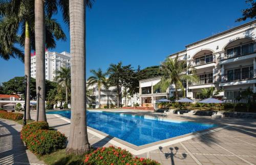 a swimming pool in front of a building with palm trees at Royal Halong Hotel in Ha Long