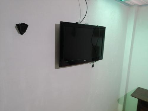 TV de pantalla plana colgada en una pared blanca en APARTA- Refugio El Retiro verde, en Leticia