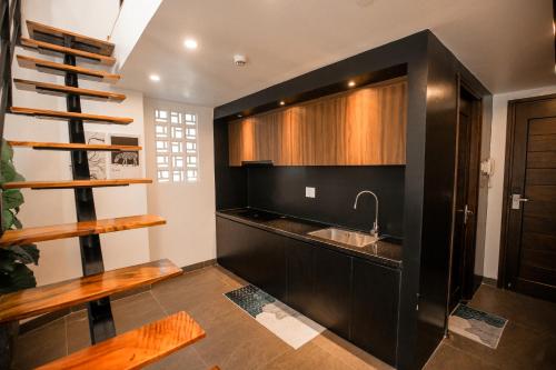 a kitchen with black cabinets and a sink and a staircase at Fati Boutique Hotel & Apartment in Vung Tau