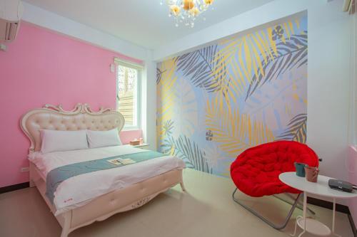 a pink bedroom with a bed and a red chair at Hualien Feel at Home BnB in Hualien City