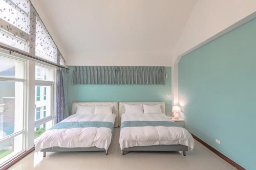 two beds in a room with a large window at Hualien Feel at Home BnB in Hualien City