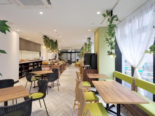 a restaurant with wooden tables and green chairs at Green Rich Hotel Tottori Ekimae (Artificial hot spring Futamata Yunohana) in Tottori
