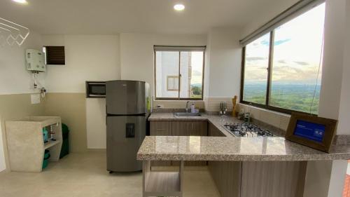 a kitchen with a refrigerator and a large window at Apartamento a 2.5 km del parque del café in Montenegro