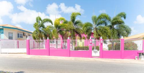 una valla rosa frente a una casa con palmeras en Aqua Villa en Willemstad