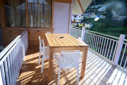 a wooden table and chairs on a porch at Munsyari The Roof Top in Munsyari
