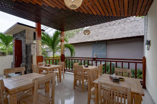 a restaurant with wooden tables and chairs on a balcony at The Pulau Bungalow in Nusa Lembongan