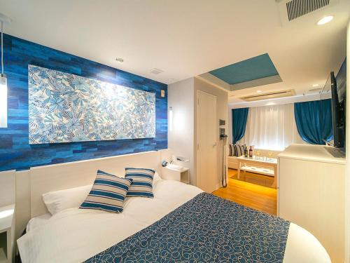 a bedroom with a bed with a blue accent wall at Hotel GT Kansai International Airport (Adult Only) in Sennan