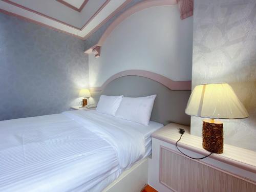 a bedroom with a bed and a lamp on a night stand at Chrysler Hotel in Taipei