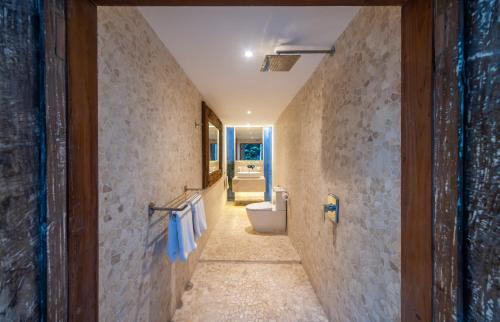 a hallway of a bathroom with a toilet and a sink at Tides Seminyak in Seminyak