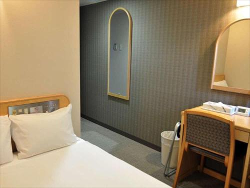 1 dormitorio con cama, escritorio y espejo en Kenchomae Green Hotel en Kumamoto