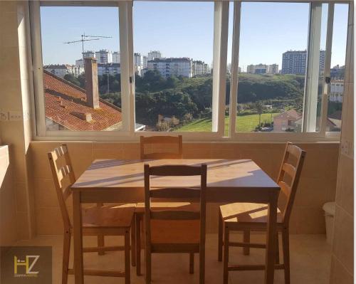 a wooden table and chairs in a room with windows at Zabava Odivelas in Odivelas