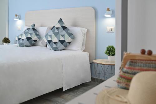 1 dormitorio con 1 cama blanca y 2 almohadas en Dimora del Corso - Rooms, en Mattinata