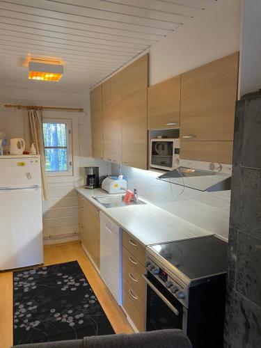 cocina con armarios de madera y nevera blanca en Arctic-maja A en Kittilä