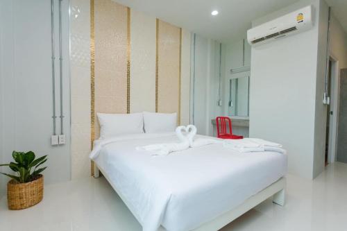 een wit bed in een kamer met een rode stoel bij Get Sleep @ท่าศาลา in Ban Pho Tai
