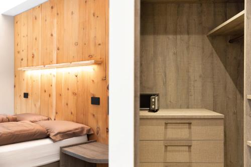 een slaapkamer met een bed en een houten muur bij Wind Mountain Planet Suite House in Livigno