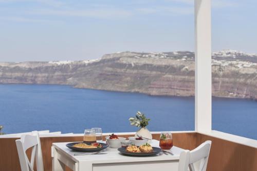 a table with plates of food on it with a view of the ocean at Apanemo Hotel & Suites in Akrotiri