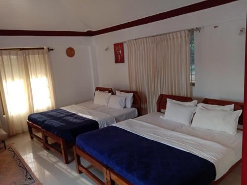 a bedroom with two beds with blue sheets at Shivalaya Homestay, Madikeri in Siddapur