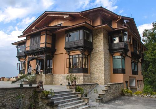 a large house with a balcony and stairs at The Chumbi Mountain Retreat & Spa, A Club Mahindra Associate in Pelling