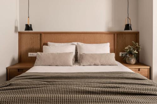 a bed with a wooden head board and pillows at Paradise Elegant Apartments - Perfect escape on the beach in Alykes