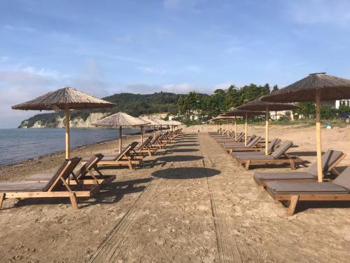 a row of chairs and umbrellas on a beach at Mediterranean Blue in Kavos