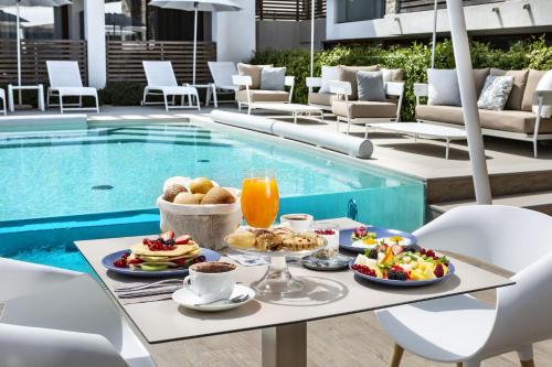 a table with breakfast food next to a swimming pool at Sandalia Boutique Hotel - Adults Only in Cannigione