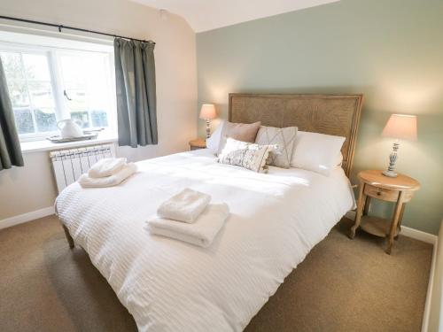 a bedroom with a large white bed with towels on it at Manor Barn Cottage in Bakewell