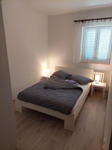 a bedroom with a bed and two tables and a window at Apartman ENA in Opatija