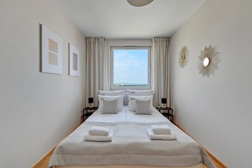 biała sypialnia z dużym łóżkiem i oknem w obiekcie Top Floor z widokiem na morze by Downtown Apartments w Gdańsku