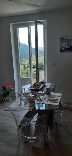 a dining room table with chairs and a large window at B&B degli Allori in Moggiona
