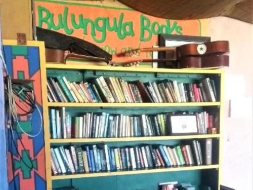 Bulungula Xhosa Community Lodge في Bulungulu: رف كتاب ممتلئ بالكثير من الكتب