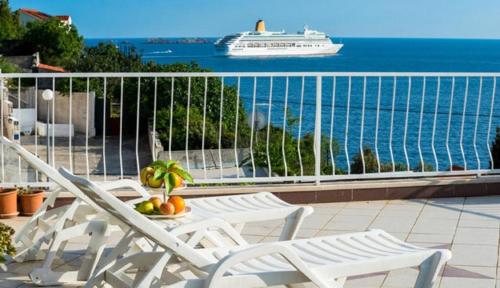 a balcony with chairs and a cruise ship in the water at Apartmani Matea in Zaton