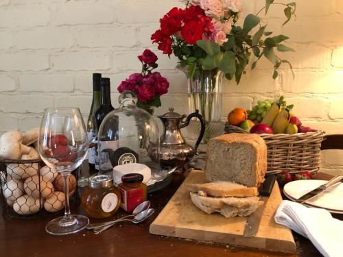 a table with a glass of wine and a basket of fruit at Battunga Cottages in Watervale