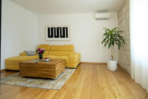 a living room with a yellow couch and a coffee table at Apartment Derossi in Umag