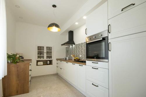 a kitchen with white cabinets and a flat screen tv at Apartment Derossi in Umag